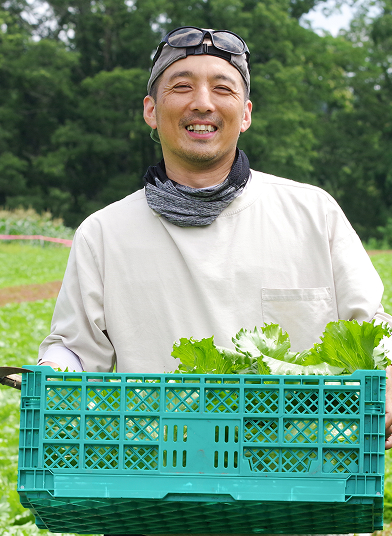 野菜カゴを持つ笑顔の農家男性